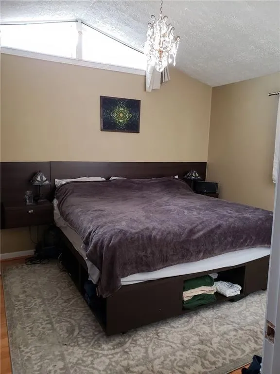 Bedroom featuring light wood-style floors, a textured ceiling, and a chandelier
