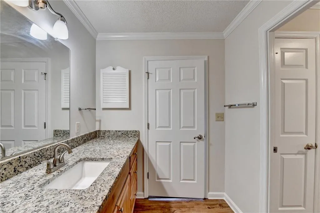 Bathroom featuring a textured ceiling, hardwood / wood-style flooring, crown molding, and vanity