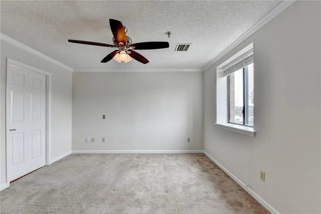 Spare room with ceiling fan, crown molding, a textured ceiling, and light colored carpet