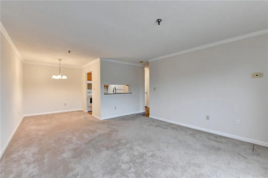 Spare room with sink, a chandelier, crown molding, and light carpet