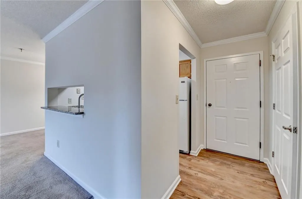 Corridor featuring light wood-type flooring, a textured ceiling, sink, and ornamental molding