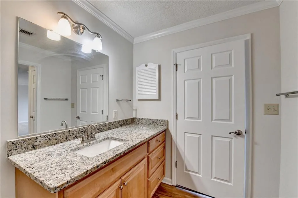 Bathroom with a textured ceiling, vanity, and ornamental molding