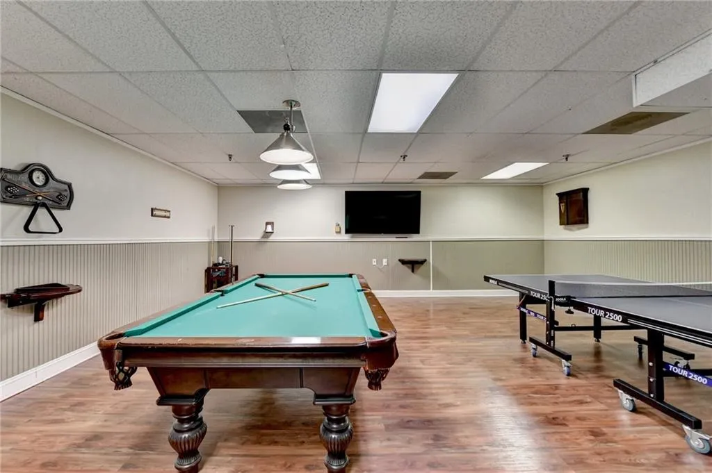 Recreation room with a paneled ceiling and wood-type flooring