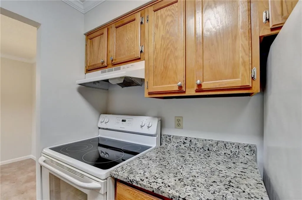 Kitchen featuring white electric range, ornamental molding, stainless steel fridge, and light stone counters