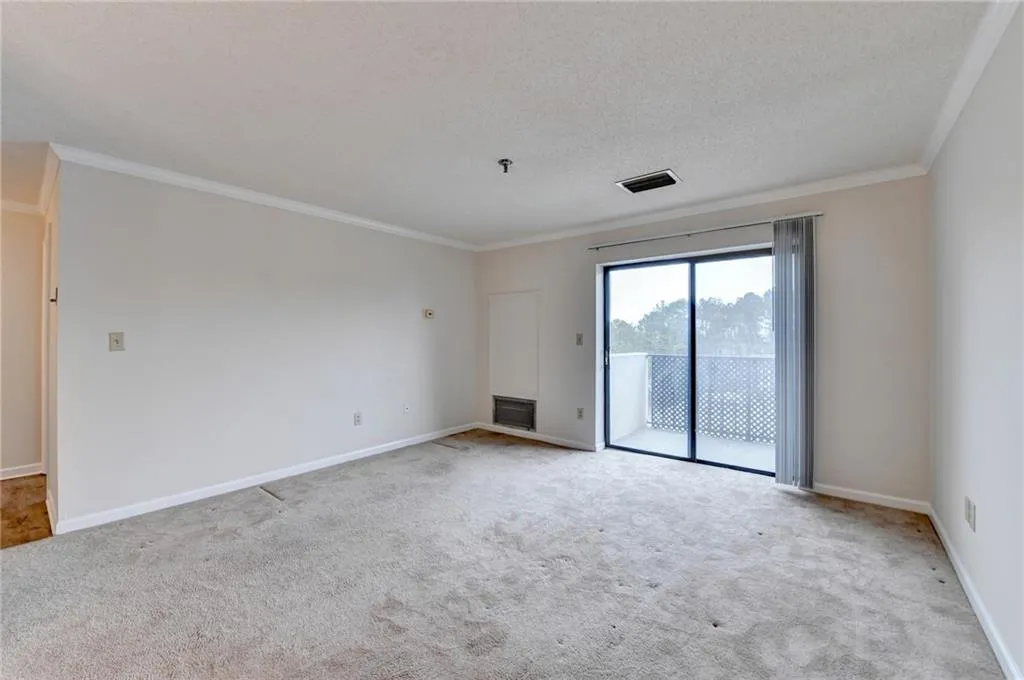 Carpeted empty room with a textured ceiling and crown molding