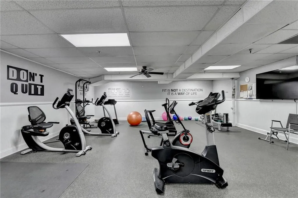 Exercise room with ceiling fan and a drop ceiling