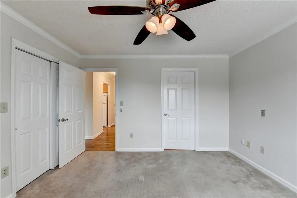Unfurnished bedroom with white refrigerator, crown molding, light carpet, and a textured ceiling