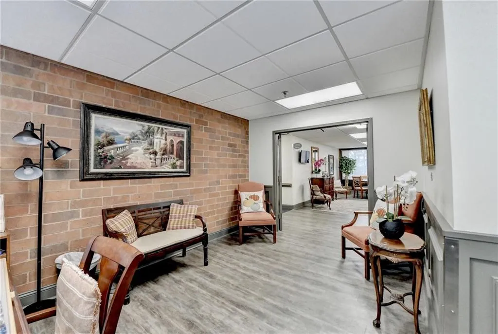 Sitting room with light hardwood / wood-style flooring, a drop ceiling, and brick wall