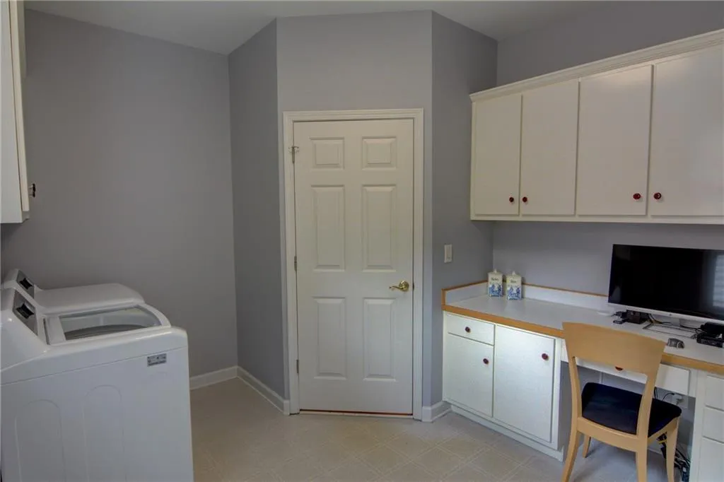 Laundry room featuring a desk, cabinet space, light flooring, and washing machine and dryer