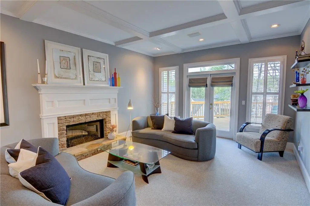 Living room with coffered ceiling, ornamental molding, french doors, carpet, and a fireplace