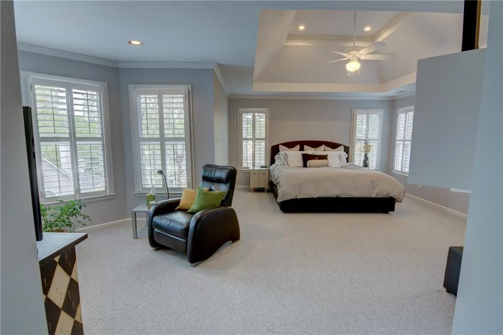 Bedroom with light carpet, recessed lighting, ceiling fan, multiple windows, and crown molding