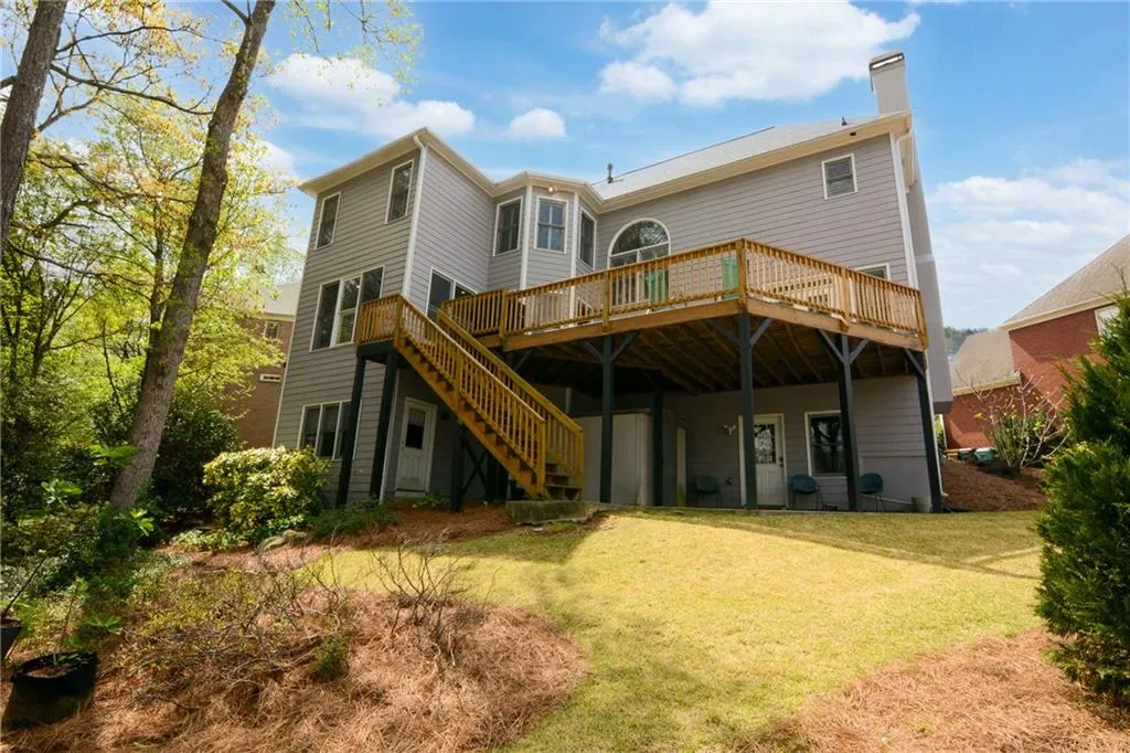 Back of property featuring a deck, a chimney, a yard, and a patio area