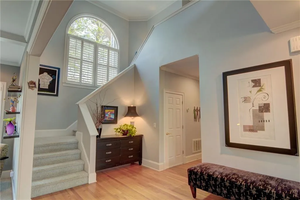 Staircase featuring ornamental molding, wood finished floors, and a high ceiling