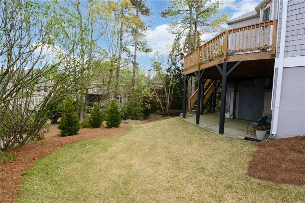 View of green lawn featuring a patio area and a deck