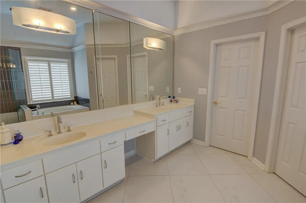 Bathroom featuring double vanity, a bath, light marble finish floors, and crown molding