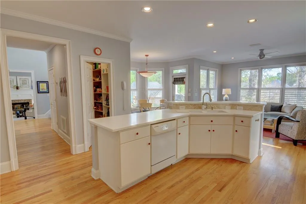 Kitchen with an island with sink, light countertops, light wood-style flooring, pendant lighting, and dishwasher