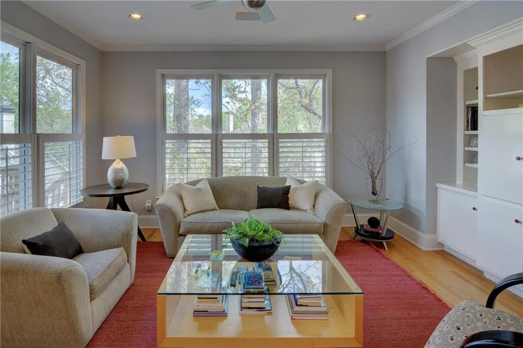 Living area with a ceiling fan, ornamental molding, wood finished floors, built in shelves, and recessed lighting