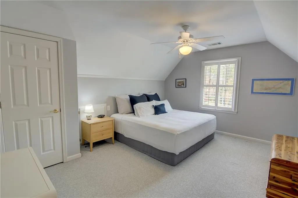 Carpeted bedroom with a ceiling fan and lofted ceiling