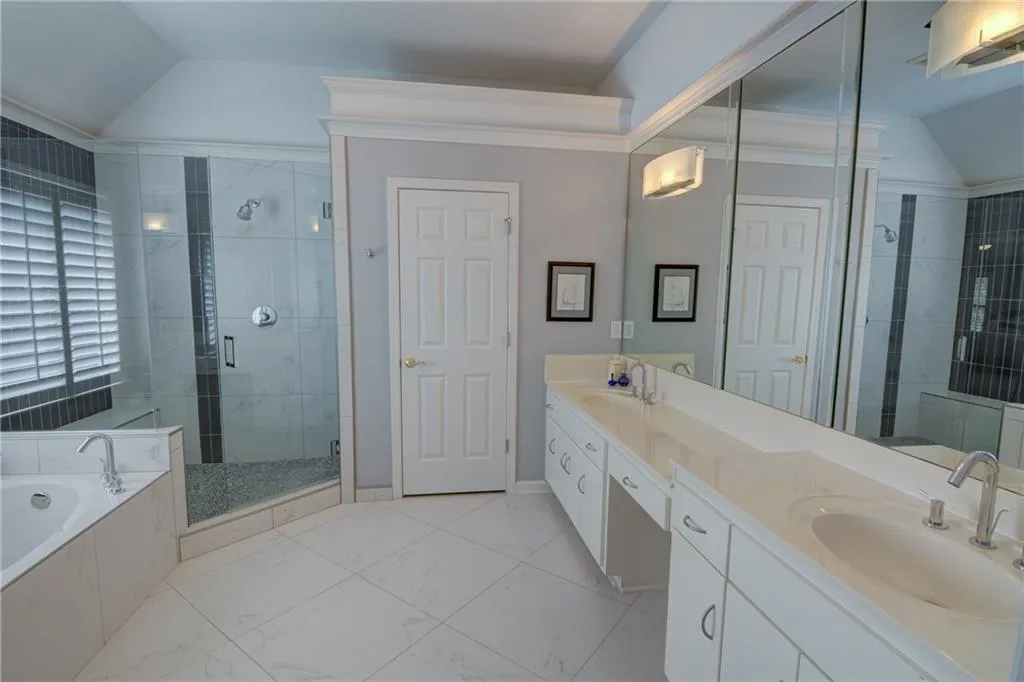 Bathroom featuring lofted ceiling, a shower stall, double vanity, and a garden tub