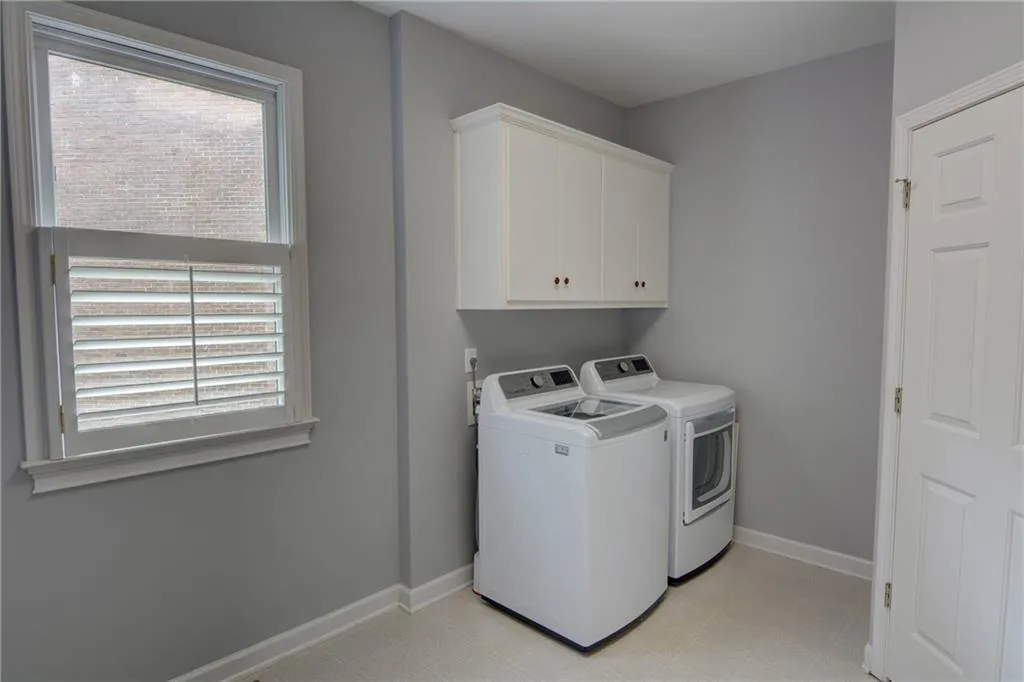 Laundry room featuring light floors, cabinet space, plenty of natural light, and separate washer and dryer