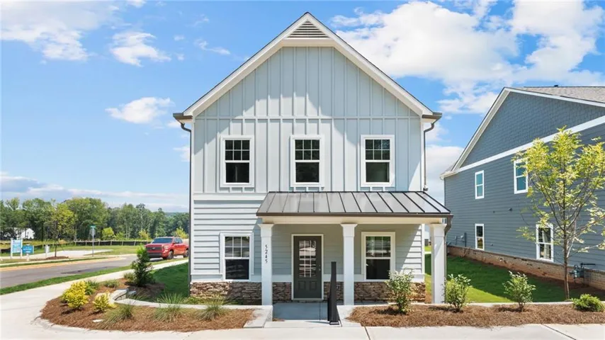 Light blue siding exterior featuring board and batten accents, a covered front porch with white columns, and a metal awning