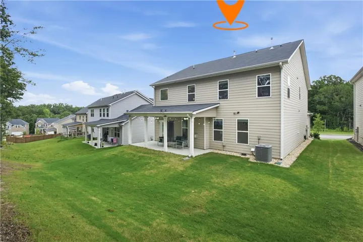 Spacious backyard featuring a covered patio, extensive green lawn, and a light-toned siding exterior