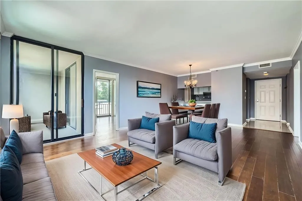 Living area with a chandelier, hardwood / wood-style flooring, ornamental molding, and baseboards