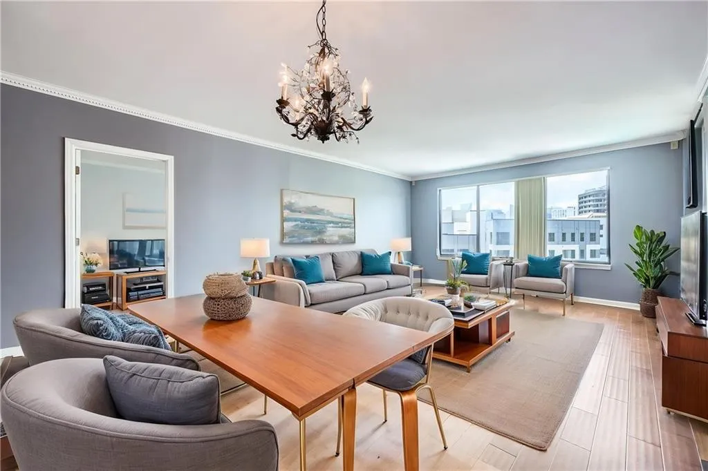 Living area with a chandelier, crown molding, light wood-style flooring, and baseboards