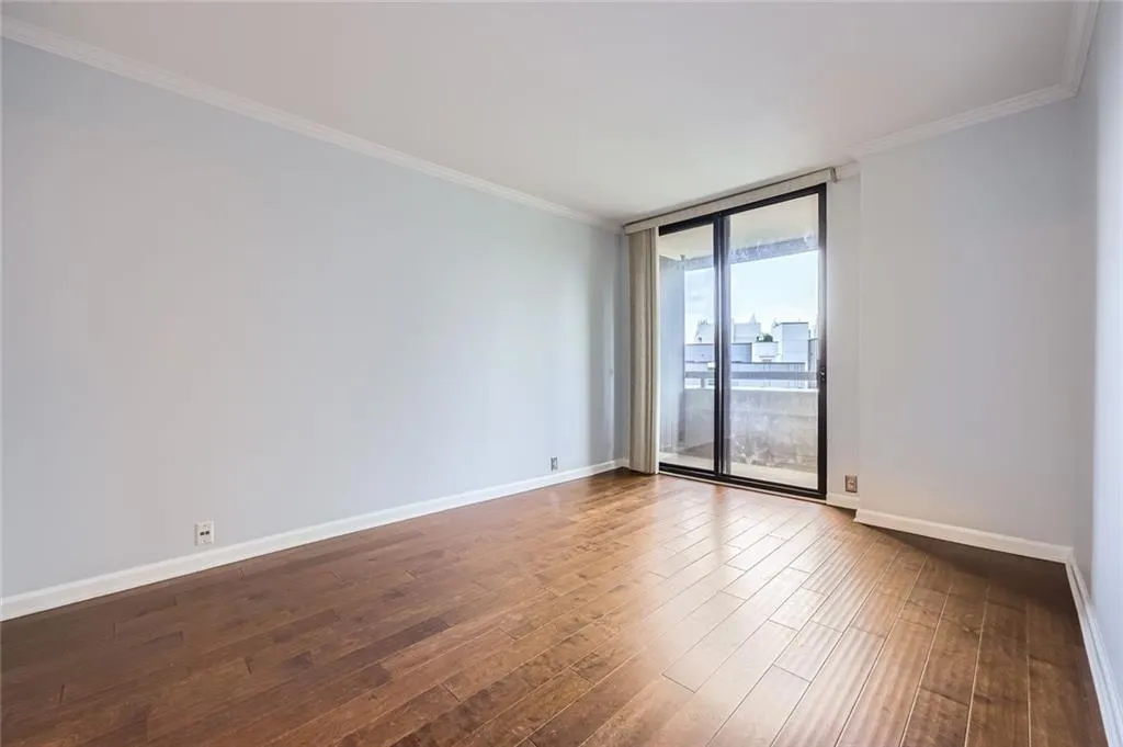 Unfurnished room featuring expansive windows, dark wood-style flooring, baseboards, and ornamental molding