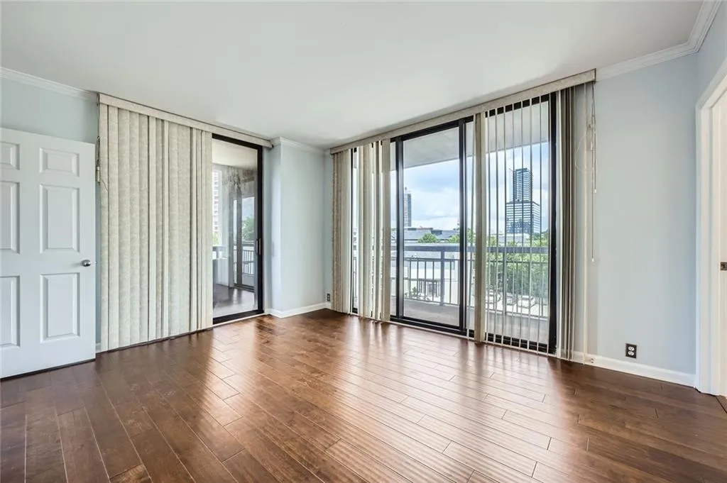 Unfurnished room with a wall of windows, crown molding, wood finished floors, and baseboards