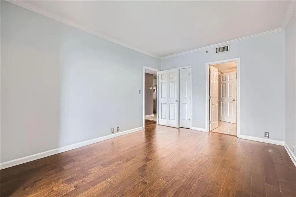 Unfurnished bedroom with hardwood / wood-style floors, baseboards, ornamental molding, and a closet