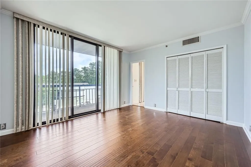 Unfurnished bedroom with access to exterior, ornamental molding, dark wood-style floors, expansive windows, and baseboards