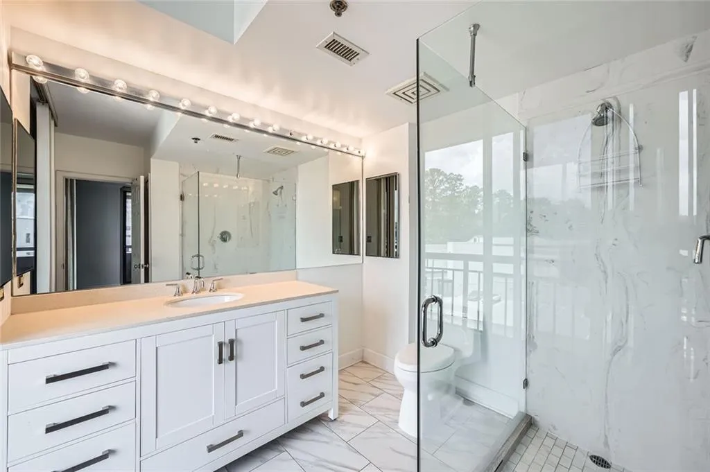 Full bath with a marble finish shower, vanity, marble finish floors, and toilet