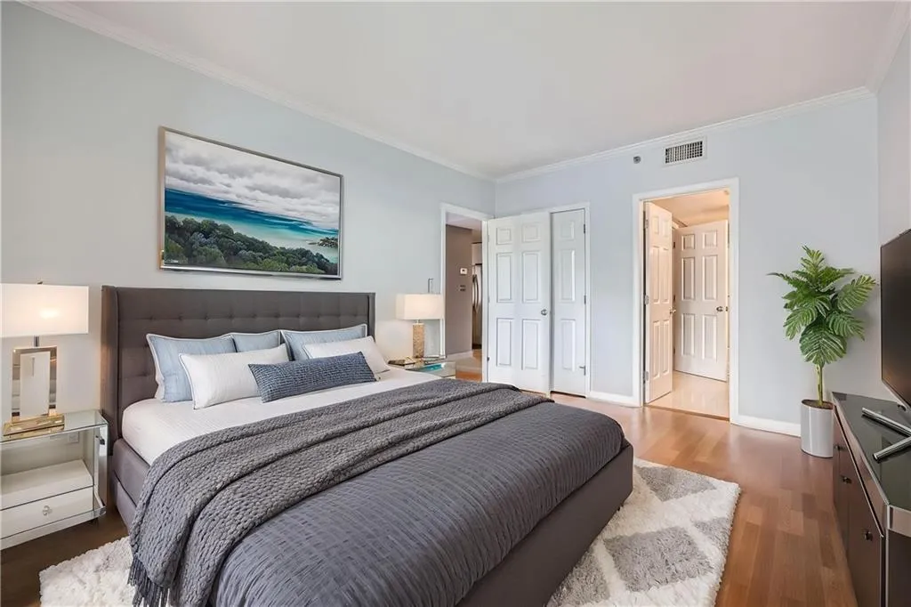 Bedroom featuring ornamental molding, wood finished floors, baseboards, and a closet