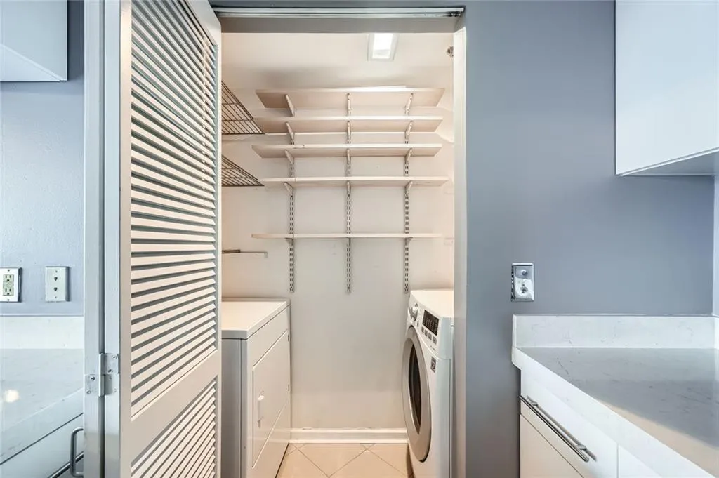 Laundry room with separate washer and dryer and light tile patterned floors
