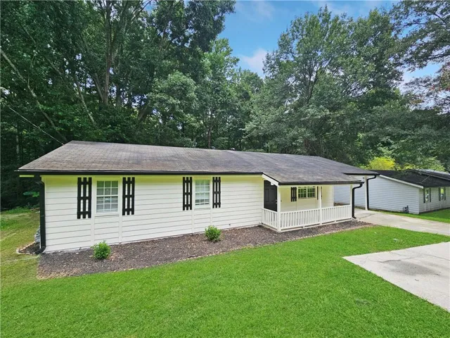 Ranch-style residence featuring white siding, a covered front porch with white railing, and decorative black window shutters