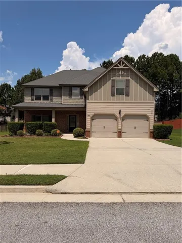 Two-story home featuring a brick and board-and-batten exterior with a peaked gable roofline