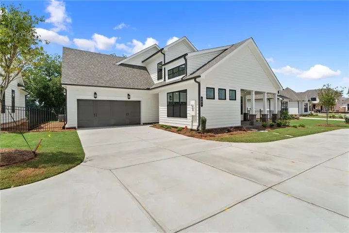 Modern farmhouse-style exterior with white siding, black-framed windows, and a covered front entry
