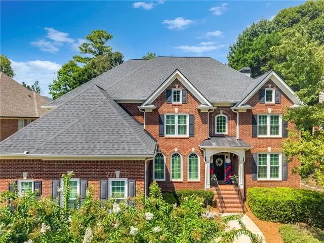 Brick exterior with a gabled roofline, multiple windows with dark shutters, an arched entry, and a covered porch
