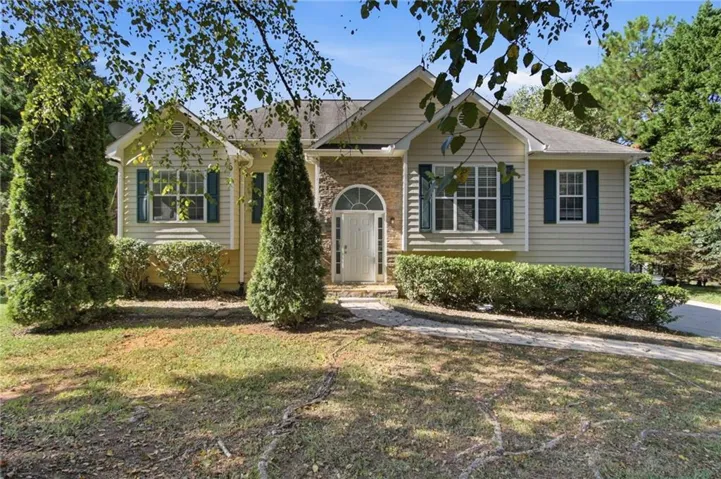 Stone accent siding on the facade, arched entryway, and multiple windows with shutters