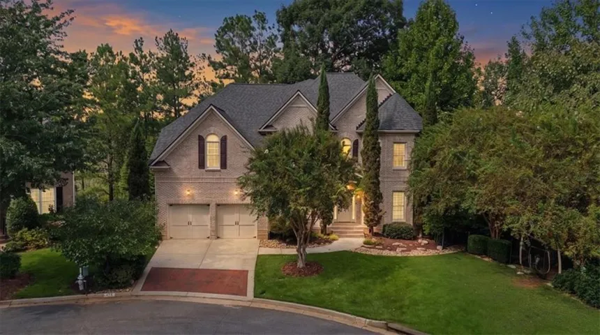 Brick exterior residence with a two-car garage, established landscaping, and a paved driveway