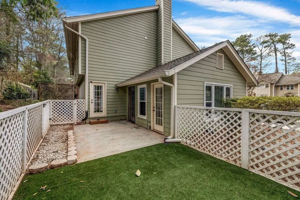 Rear view of house featuring a patio, a yard, a fenced backyard, and a chimney
