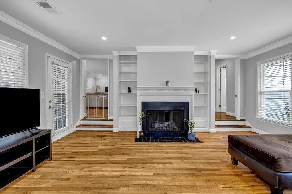 Living room with crown molding, light wood-style floors, and visible vents