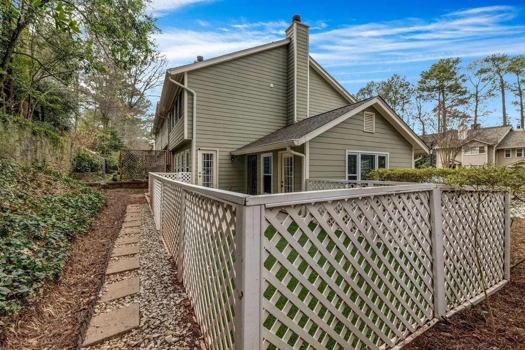 View of side of home featuring a chimney and fence