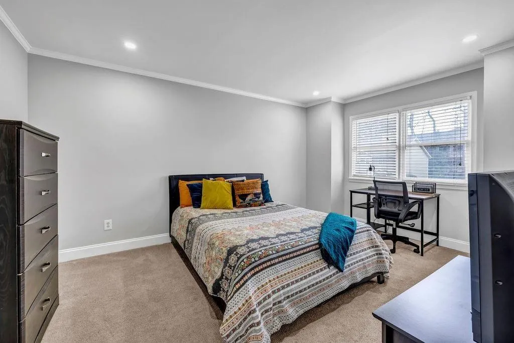 Bedroom featuring baseboards, light carpet, and crown molding