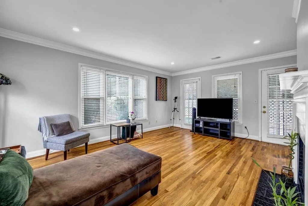 Living room featuring light wood finished floors, visible vents, and crown molding