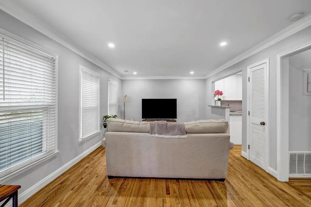 Living room with visible vents, baseboards, light wood-style floors, and crown molding