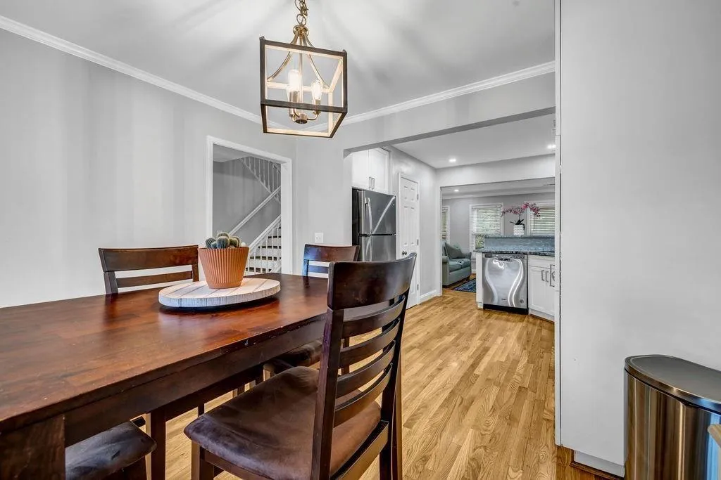 Dining area featuring baseboards, stairway, ornamental molding, light wood-style flooring, and a notable chandelier