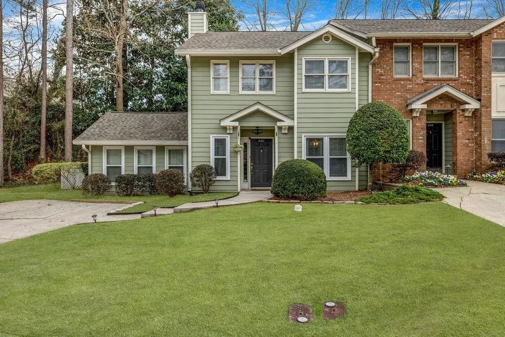 View of front of house with a chimney, a front lawn, and a shingled roof