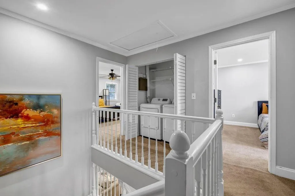 Hall with baseboards, washer and clothes dryer, attic access, ornamental molding, and carpet floors